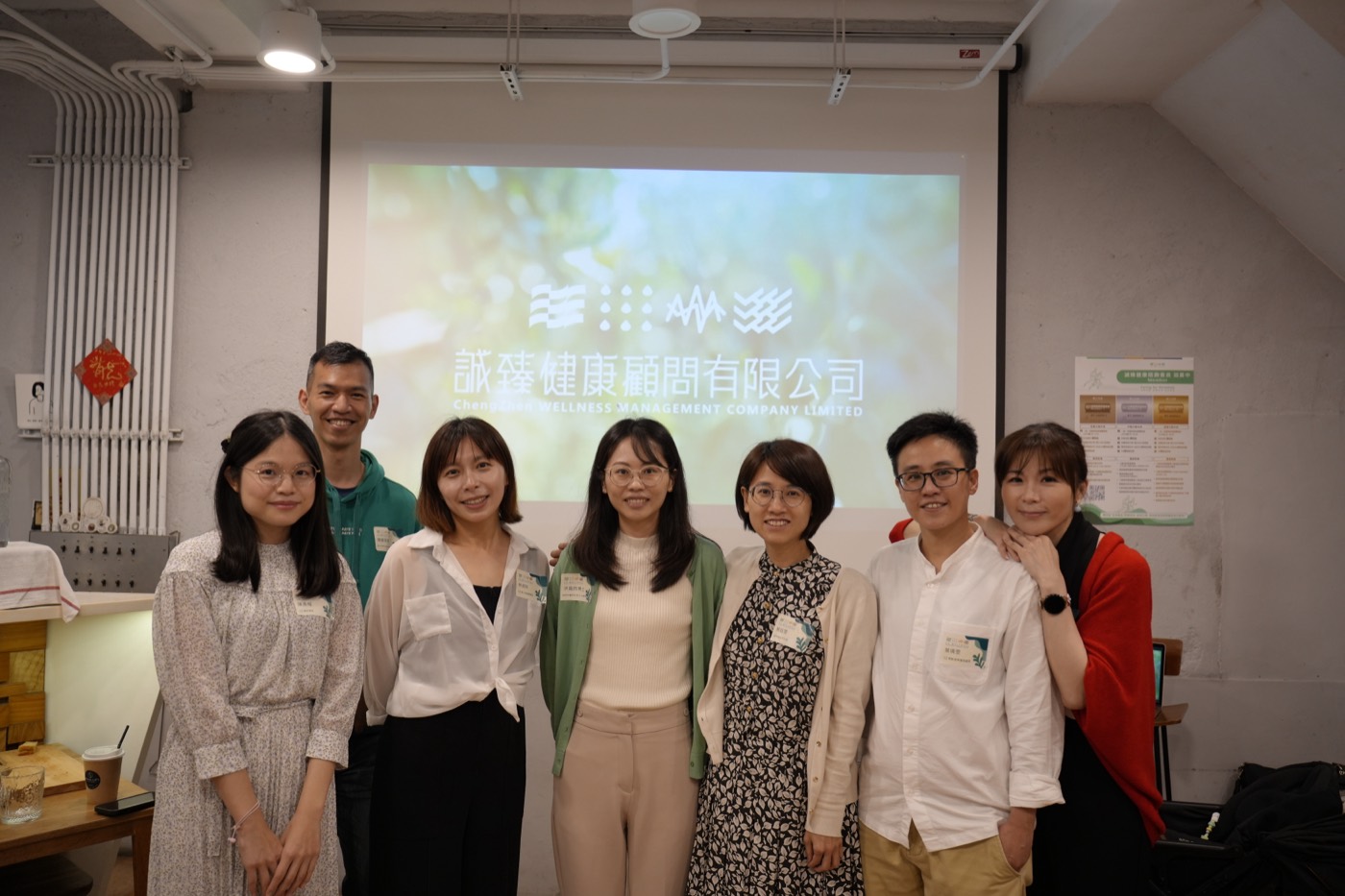 誠臻健康團隊七位成員在品牌發佈會的投影幕前合影